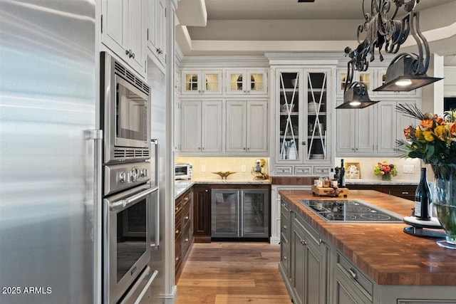 kitchen featuring wooden counters, built in appliances, hardwood / wood-style floors, decorative backsplash, and white cabinets