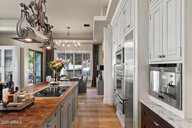 kitchen with white cabinetry, wooden counters, black electric cooktop, and hardwood / wood-style flooring