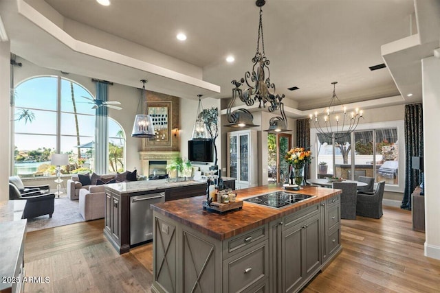 kitchen featuring hardwood / wood-style floors, dishwasher, wooden counters, a center island, and a raised ceiling