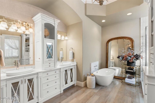 bathroom with hardwood / wood-style flooring, vanity, crown molding, and a bathtub