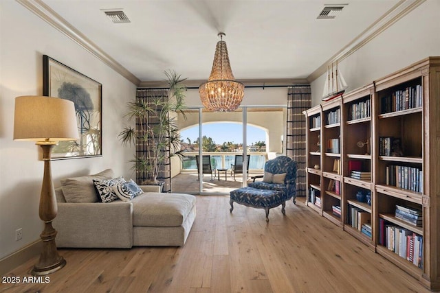 living area featuring crown molding, a water view, wood-type flooring, and an inviting chandelier