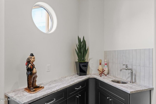 bar featuring sink, backsplash, and light stone countertops