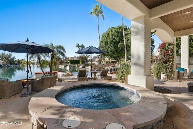 view of swimming pool with an in ground hot tub, a water view, and a patio area