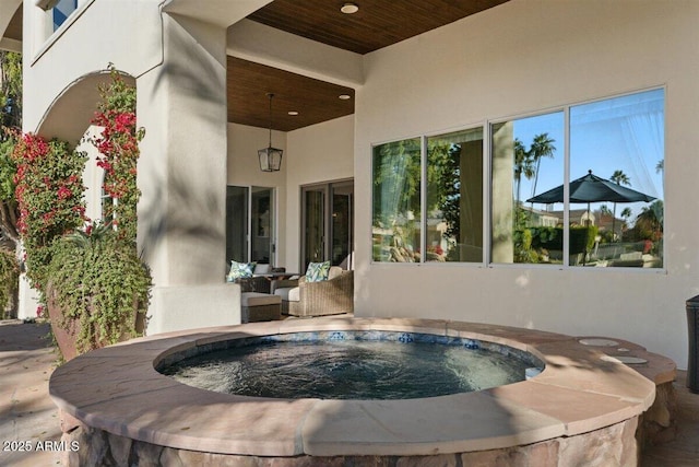 exterior space with an outdoor hot tub and a patio area