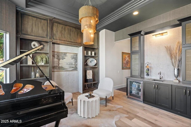 interior space with crown molding, wine cooler, light hardwood / wood-style floors, built in shelves, and wet bar