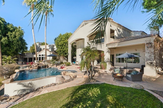 back of property with pool water feature, a patio, and a fire pit