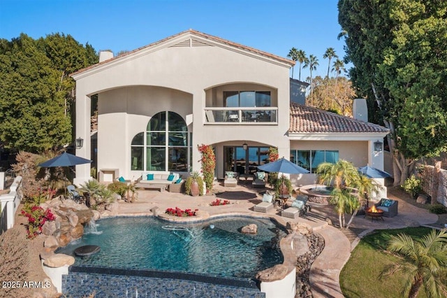 rear view of property featuring a patio, a balcony, and pool water feature