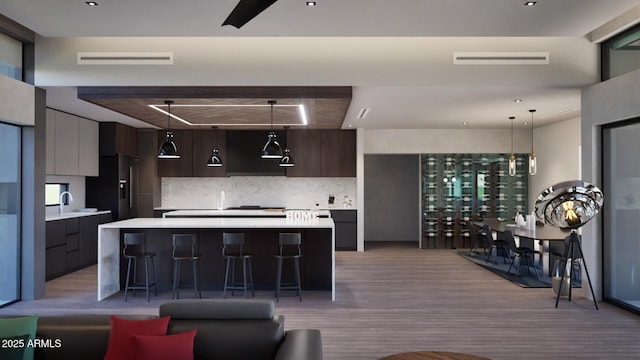 kitchen with a breakfast bar area, black fridge with ice dispenser, dark brown cabinets, light hardwood / wood-style flooring, and a center island