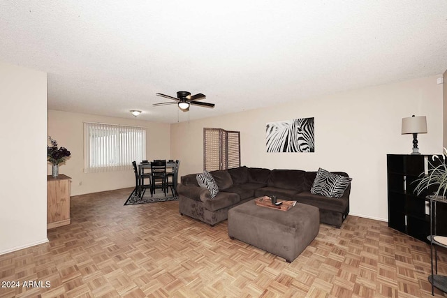 living room with ceiling fan, light parquet flooring, and a textured ceiling