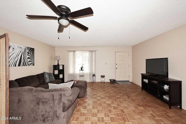 living room featuring ceiling fan, light parquet floors, and a textured ceiling