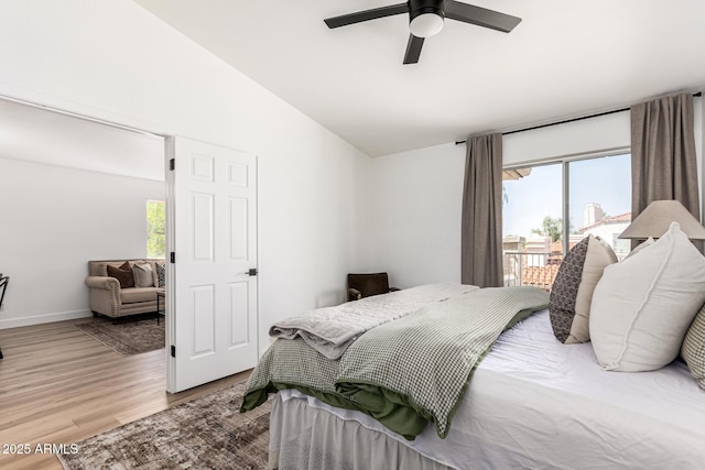 bedroom featuring vaulted ceiling, multiple windows, access to outside, and wood finished floors
