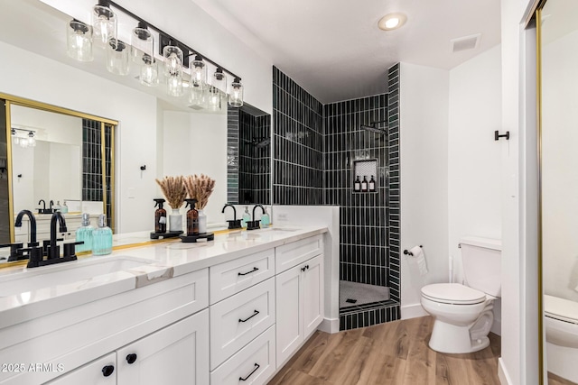 bathroom featuring toilet, visible vents, a sink, and wood finished floors