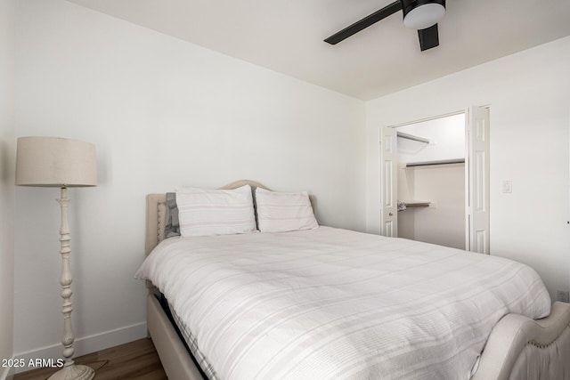 bedroom with a ceiling fan, a closet, baseboards, wood finished floors, and a spacious closet