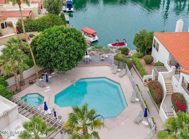 community pool featuring a fenced backyard, a patio area, a water view, and a community hot tub