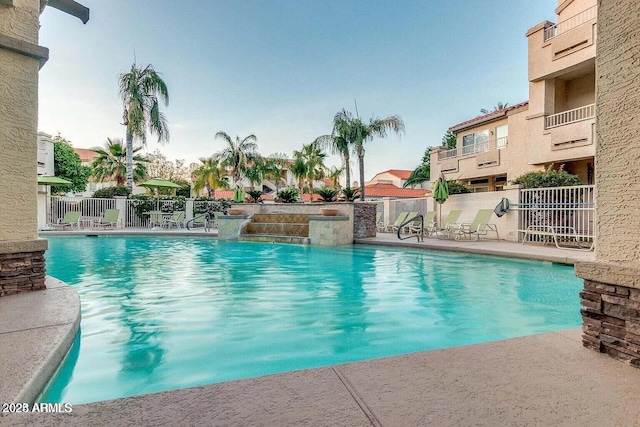 community pool with a patio and fence