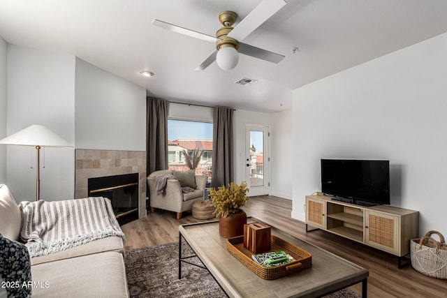 living area with visible vents, wood finished floors, a fireplace, and ceiling fan