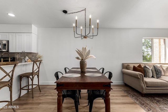 dining room featuring a chandelier, light wood-style flooring, and baseboards
