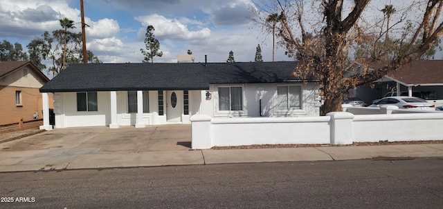 ranch-style house with stucco siding, a shingled roof, and a fenced front yard