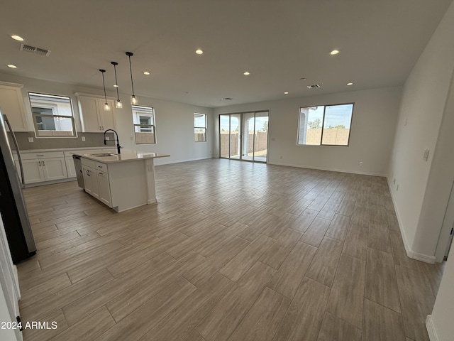 kitchen with pendant lighting, a center island with sink, sink, appliances with stainless steel finishes, and white cabinetry