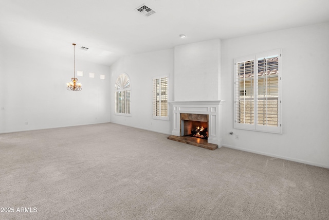 unfurnished living room with a fireplace, light carpet, and an inviting chandelier