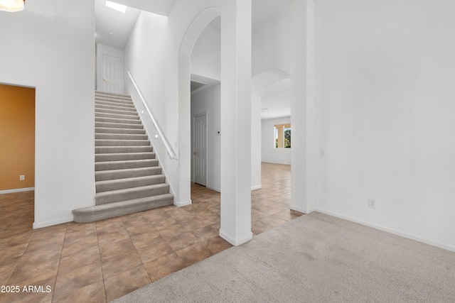 staircase featuring a towering ceiling and tile patterned floors