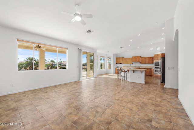 unfurnished living room with sink, light tile patterned flooring, ceiling fan, and vaulted ceiling