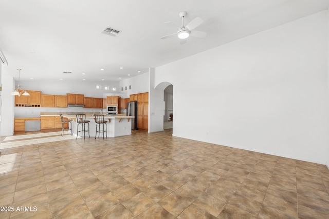 unfurnished living room with ceiling fan and a towering ceiling