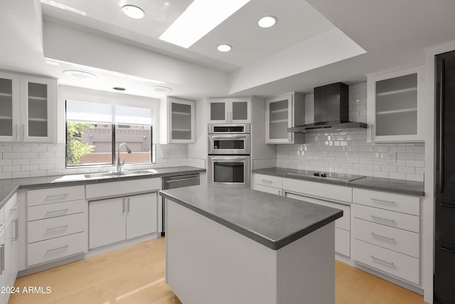 kitchen featuring backsplash, a kitchen island, white cabinetry, appliances with stainless steel finishes, and wall chimney exhaust hood