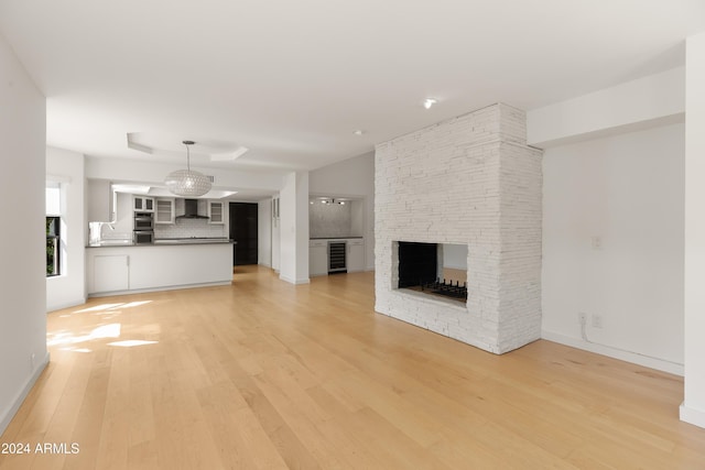 unfurnished living room featuring wine cooler, a fireplace, and light hardwood / wood-style flooring