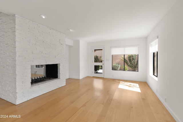 unfurnished living room with light hardwood / wood-style flooring and a stone fireplace