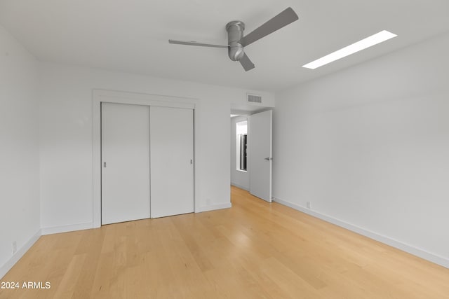 unfurnished bedroom featuring ceiling fan, a closet, and light wood-type flooring