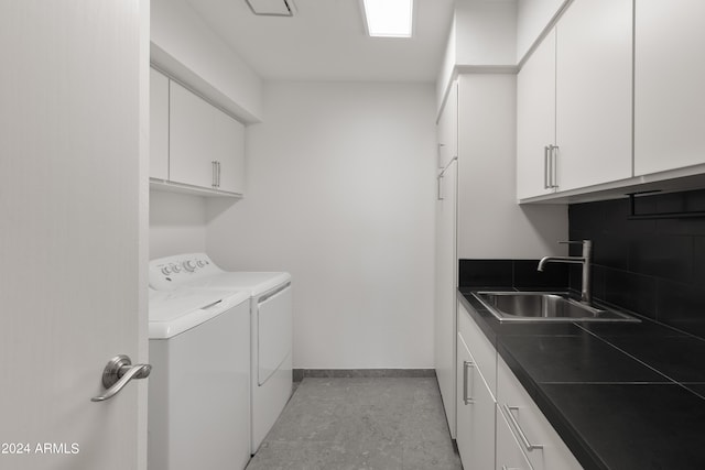 washroom with sink, washing machine and clothes dryer, and cabinets