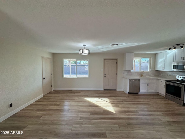 kitchen featuring white cabinetry, sink, decorative backsplash, stainless steel appliances, and light hardwood / wood-style flooring