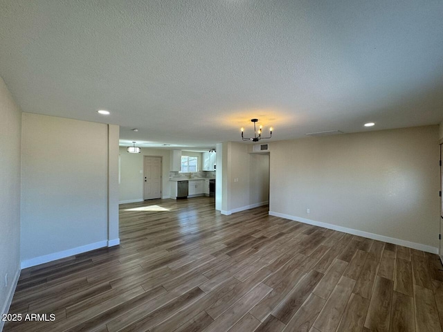 empty room with dark hardwood / wood-style floors, a textured ceiling, and a notable chandelier