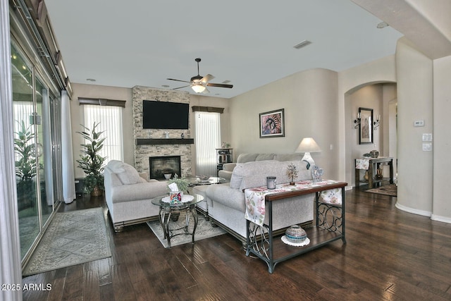 living room with dark wood-type flooring, ceiling fan, and a fireplace