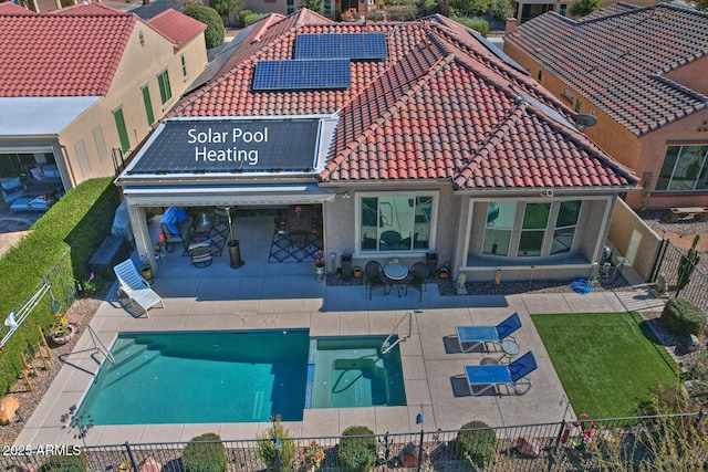 back of house with solar panels, a fenced in pool, and a patio area