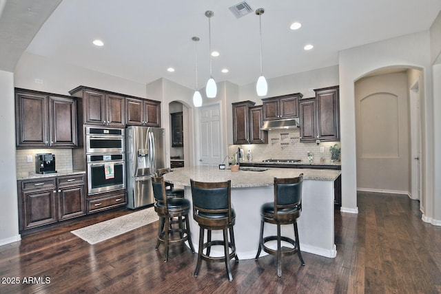 kitchen with sink, a breakfast bar area, appliances with stainless steel finishes, pendant lighting, and a kitchen island with sink