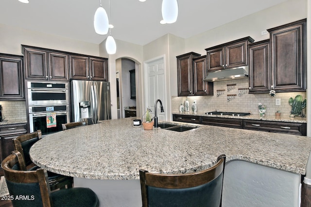 kitchen with stainless steel appliances, a center island with sink, a breakfast bar, and sink