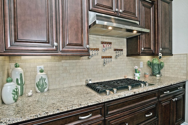 kitchen featuring stainless steel gas stovetop, light stone countertops, and backsplash