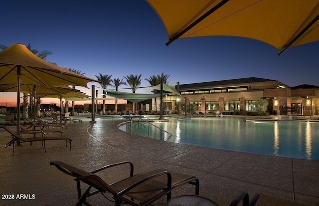 pool at dusk with a patio area