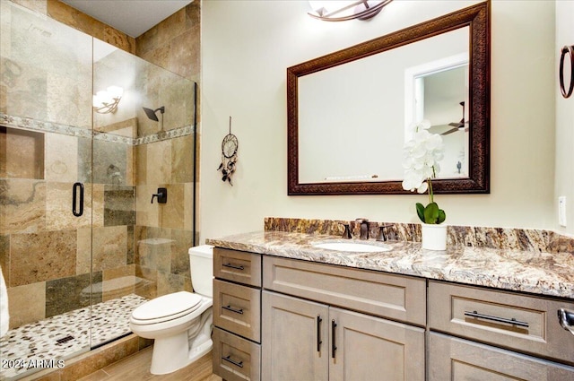 bathroom with a shower with shower door, vanity, and toilet