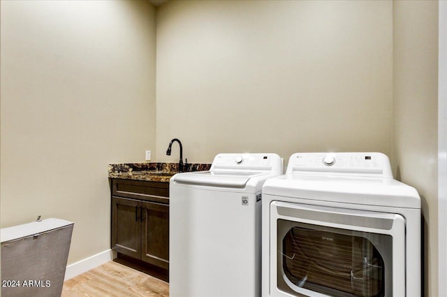 laundry area with cabinets, separate washer and dryer, and light hardwood / wood-style floors