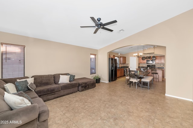 living area featuring baseboards, visible vents, arched walkways, vaulted ceiling, and ceiling fan with notable chandelier