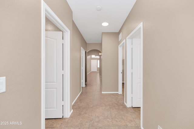 hallway featuring arched walkways, visible vents, and baseboards