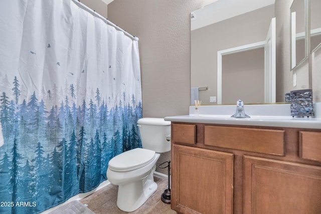 bathroom featuring toilet, a textured wall, tile patterned flooring, and vanity