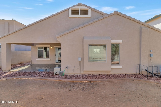 back of property featuring a patio, a tile roof, fence, and stucco siding