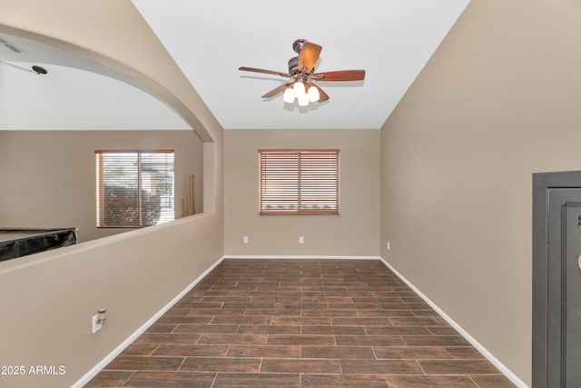 unfurnished room with lofted ceiling, ceiling fan, arched walkways, baseboards, and dark wood finished floors