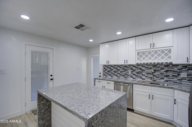 kitchen with a kitchen island, white cabinetry, dishwasher, sink, and light wood-type flooring