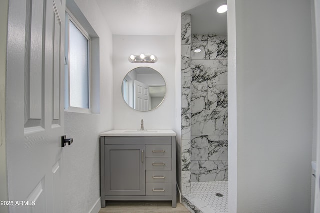 bathroom featuring a tile shower, vanity, and hardwood / wood-style floors