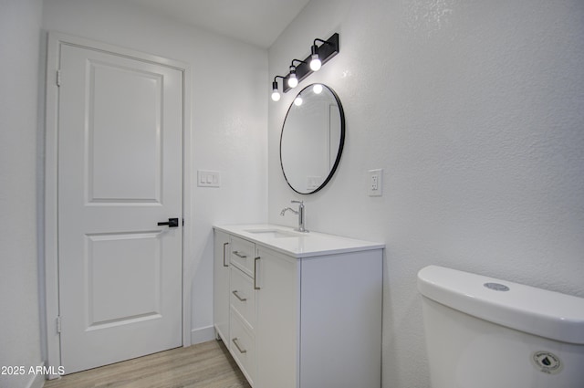 bathroom with vanity, toilet, and hardwood / wood-style floors